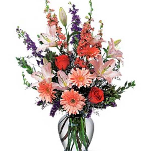 Mixed bouquet of lilies, roses, and daisies in a glass vase