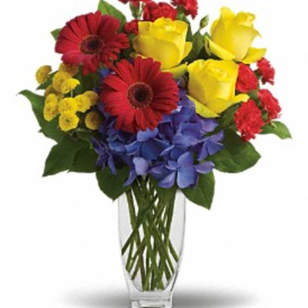 Bouquet of red, yellow, and blue flowers in a clear glass vase