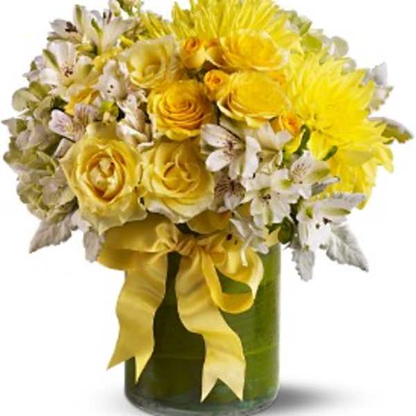 Yellow roses and white flowers in a green glass vase with a yellow ribbon