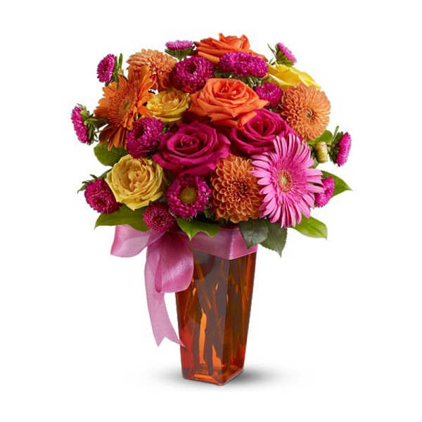 Mixed bouquet of roses and daisies in an amber vase with a pink ribbon