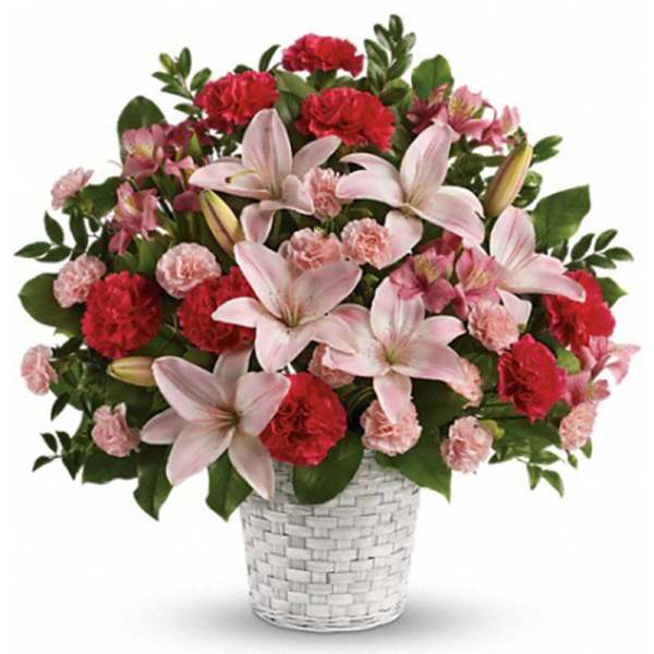 Pink lilies and pink and red carnations in a white woven basket