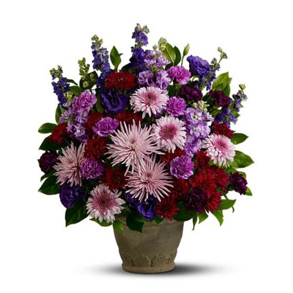 Tall arrangement of purple, red, and pink flowers in a stone-style pot