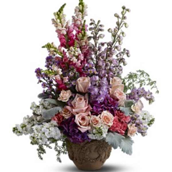 Tall arrangement of pink roses, purple flowers, and white blooms in an ornate brown urn