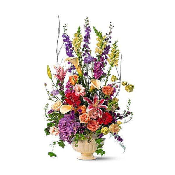 Tall mixed flower arrangement in a cream vase with lilies and roses