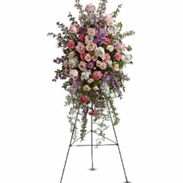 Tall standing spray of pink roses, carnations, and purple flowers on a metal easel