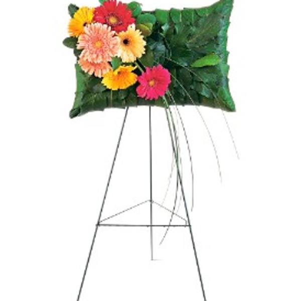 Pillow-shaped green leaf display with bright gerbera daisies on a tall metal easel.