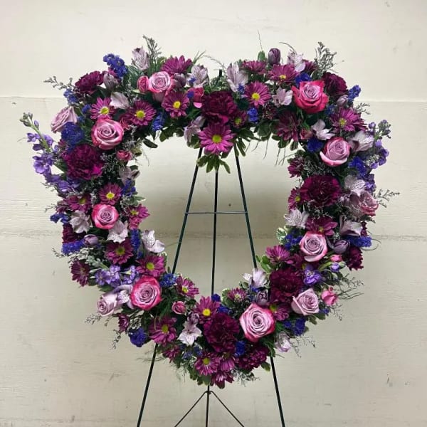 Heart-shaped standing wreath of pink and purple flowers on a metal easel