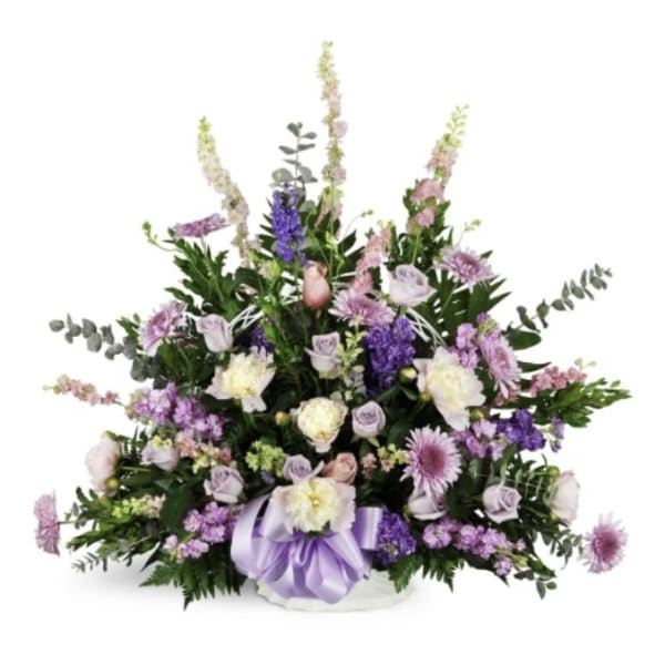Lavender and white floral arrangement in a white basket with a purple ribbon