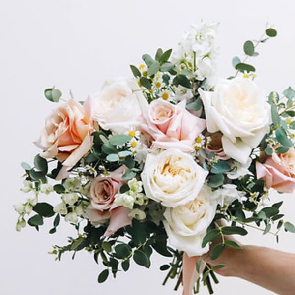 Handheld bouquet of blush and white roses with greenery