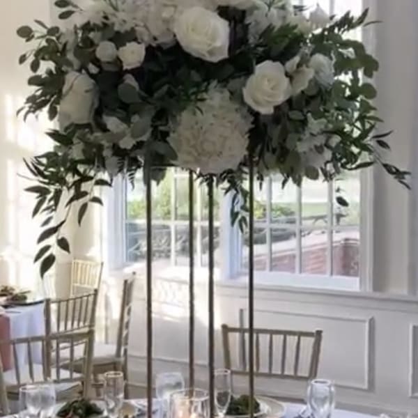 Tall white floral centerpiece on a gold stand above a banquet table