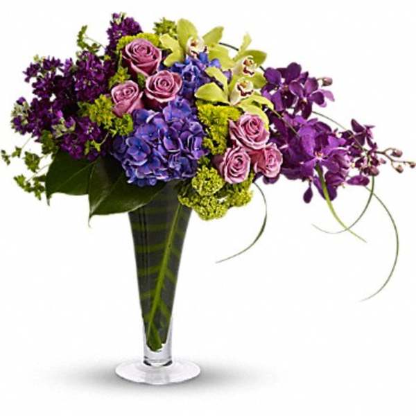 Purple and pink floral arrangement in a tall glass vase