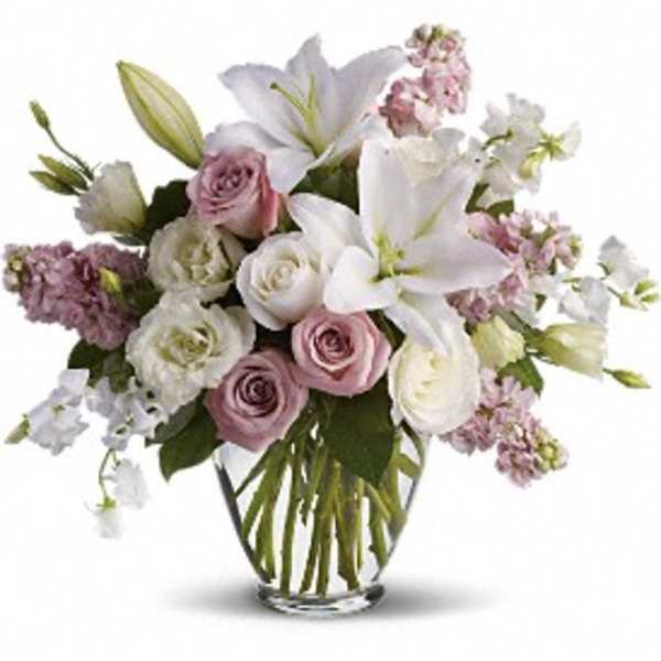 Bouquet of white lilies and pink roses in a clear glass vase