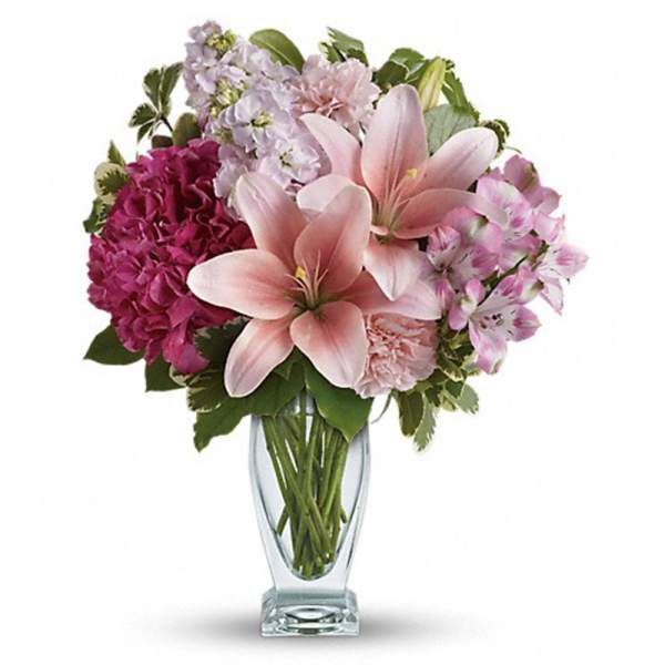 Pink lilies and mixed blooms in a clear glass vase