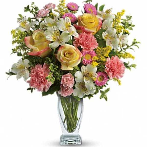 Mixed bouquet of roses, lilies, and carnations in a clear glass vase