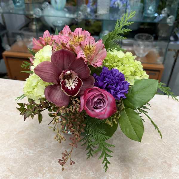 Mixed bouquet with pink, purple, and green flowers in a low vase