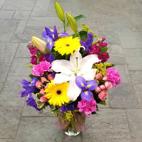 Colorful mixed bouquet with lilies, gerbera daisies, and roses in a glass vase