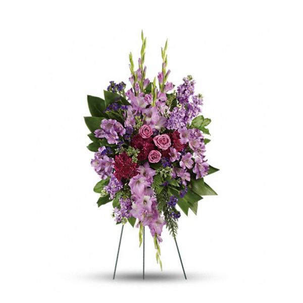 Tall standing spray of purple and lavender flowers with pink roses on a metal easel