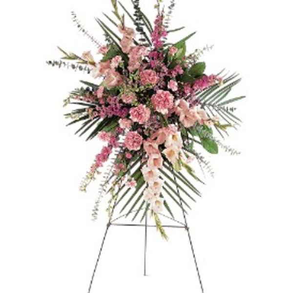 Tall pink carnation and snapdragon standing spray with palm fronds on a metal easel