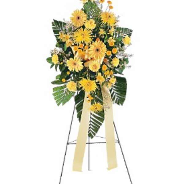 Tall standing spray of yellow daisies and mums on an easel with long yellow ribbons
