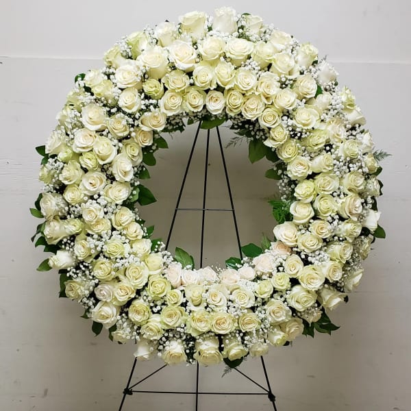 Large white rose wreath on a black stand