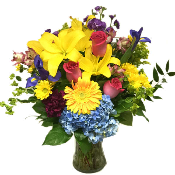 Colorful mixed bouquet in a glass vase with lilies, roses, and hydrangeas