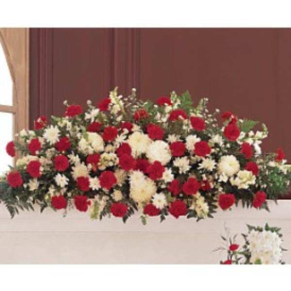 Red and white carnation and mum casket spray arranged in a long, low design