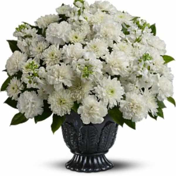 Large all-white carnation and chrysanthemum arrangement in a dark pedestal urn