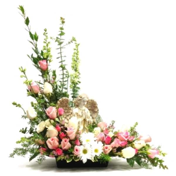 Sympathy arrangement of pink and white roses with a central angel figurine in a low black container