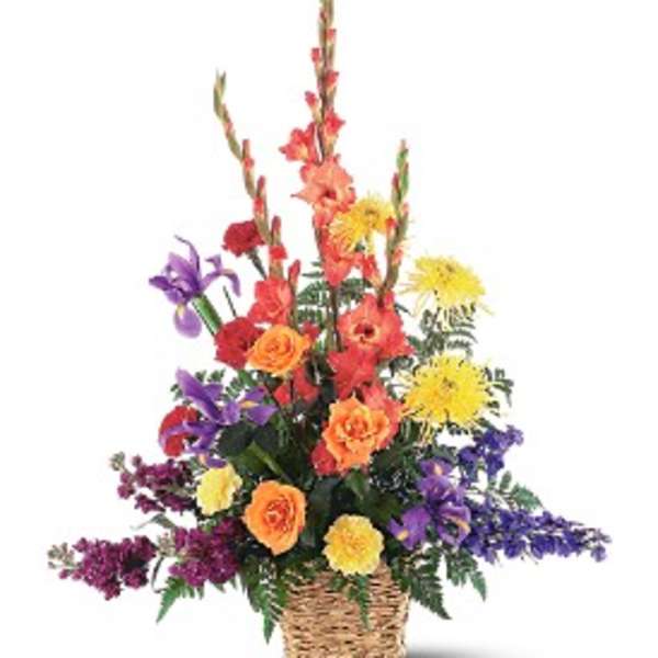 Tall mixed basket arrangement with orange gladiolus, roses, yellow mums, and purple flowers