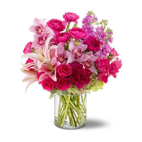 Pink roses and lilies arranged in a clear glass vase