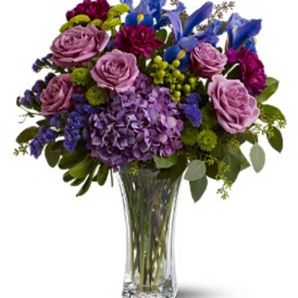 Purple and blue floral bouquet in a clear glass vase