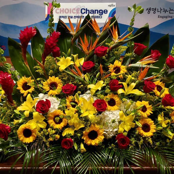 Large altar arrangement with yellow lilies, sunflowers, red roses and tropical flowers in a fan shape