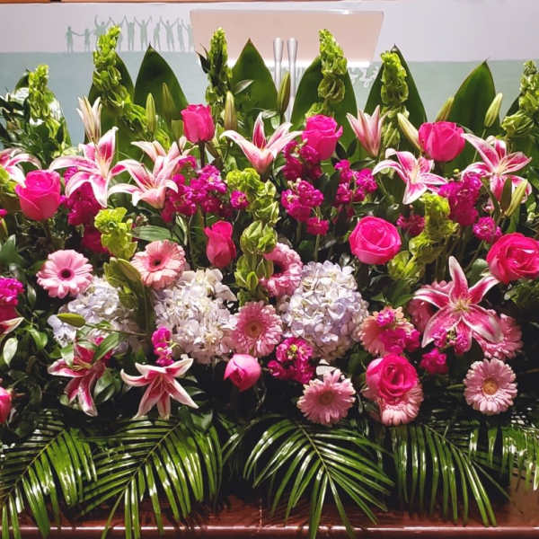 Large pink and white floral arrangement with roses, lilies, hydrangeas and gerberas in a low, wide display