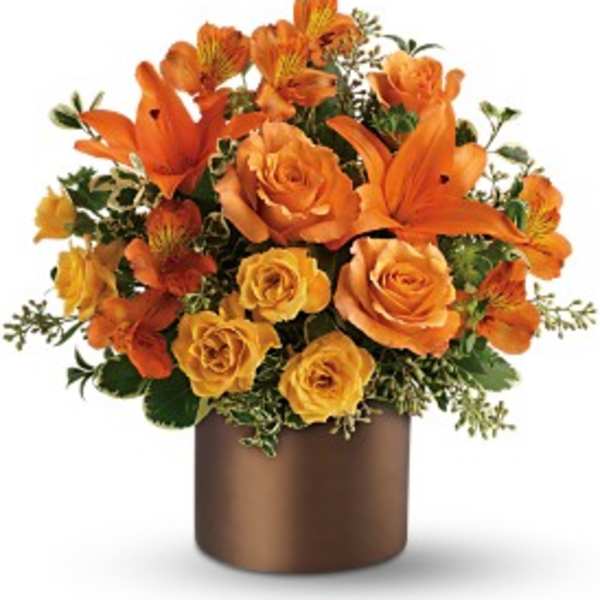 Orange lilies and roses in a bronze cylinder vase with compact mixed arrangement