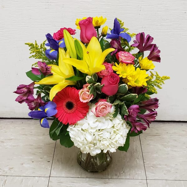 Mixed bouquet with lilies, roses, gerbera daisies, and hydrangea in a glass vase