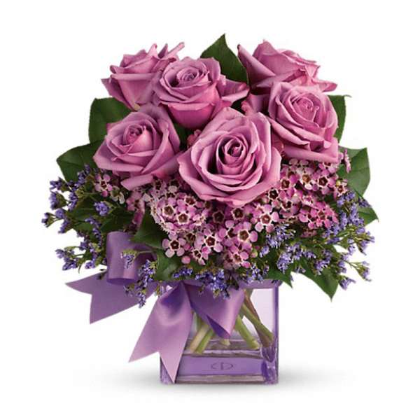 Bouquet of lavender roses and purple filler flowers in a square glass vase