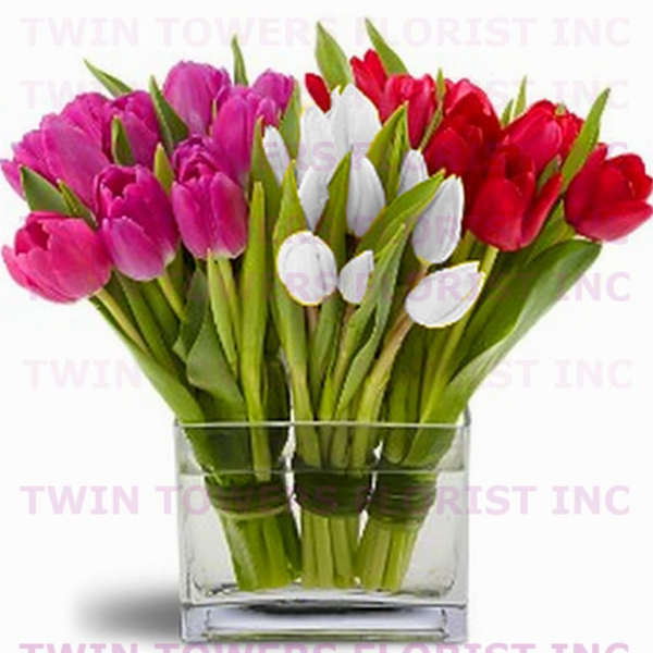 Pink, white, and red tulips arranged in a clear glass vase