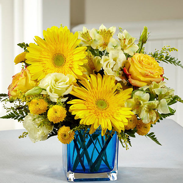 Yellow and white mixed bouquet in a blue glass vase