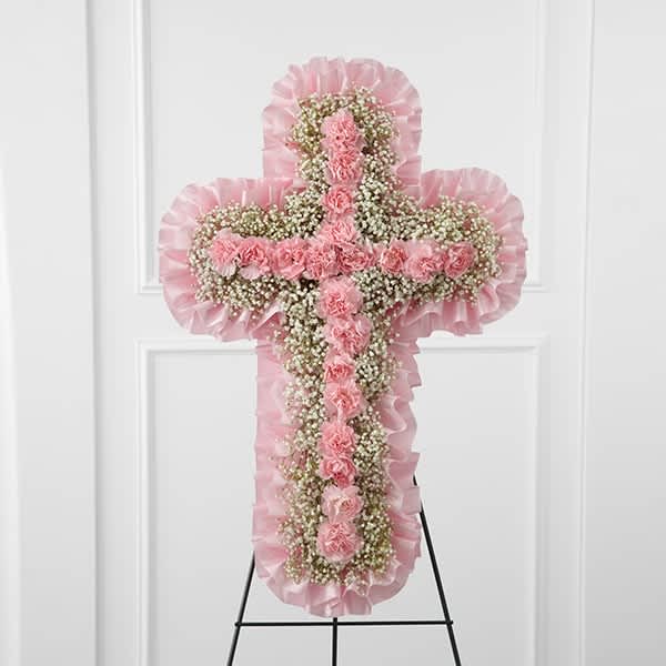 Pink floral cross on a stand with ruffled trim