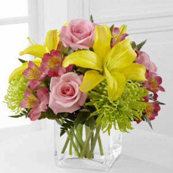 Pink roses and yellow lilies in a clear glass vase