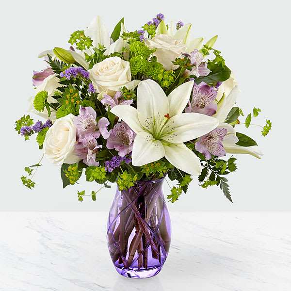 White lilies and roses in a purple glass vase