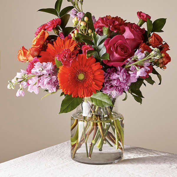 Mixed bouquet of pink and orange flowers in a clear glass vase
