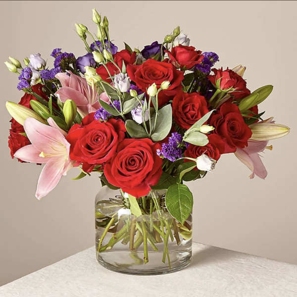 Bouquet of red roses and pink lilies in a clear glass vase