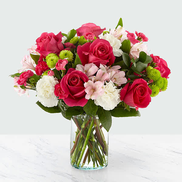 Pink and white mixed bouquet with roses and carnations arranged in a clear glass vase