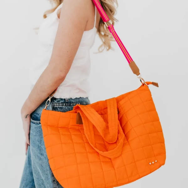 Person wearing an orange quilted tote bag with a pink strap