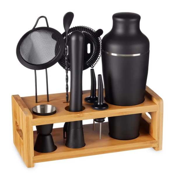 Black cocktail shaker set with strainer and jigger on a wooden stand