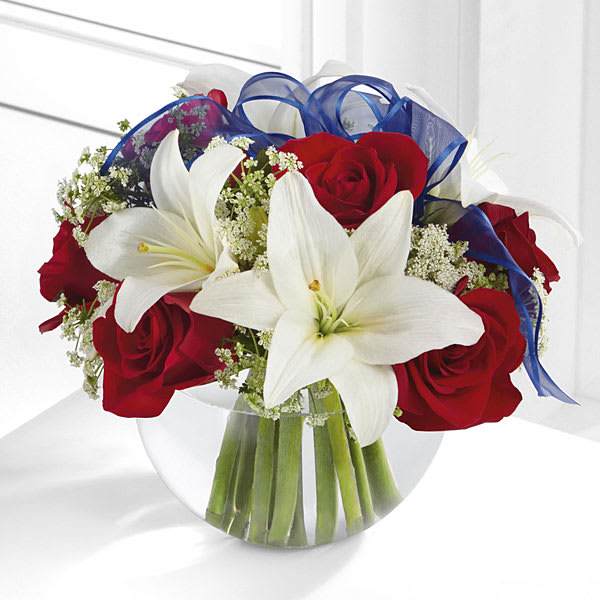 Bouquet of red roses and white lilies with blue ribbon in a glass vase