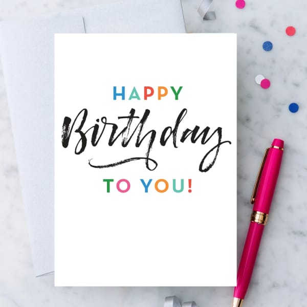 Birthday card with colorful text beside a pink pen