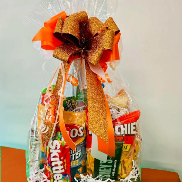 Basket of assorted snack bags wrapped in clear cellophane with a large orange bow