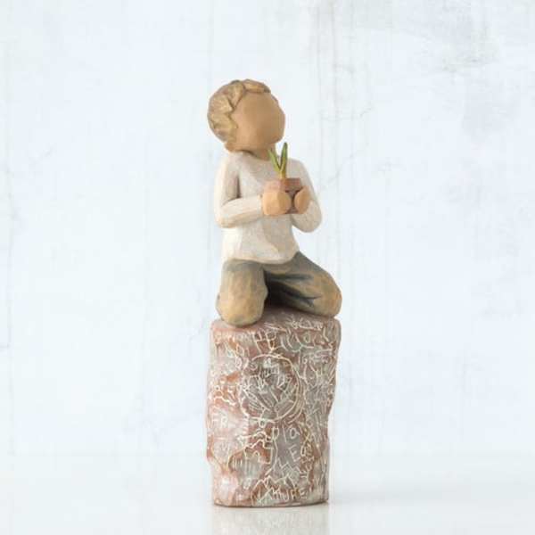 Wooden figurine of a kneeling child holding a small flower